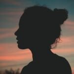 Silhouette of a person against a vibrant sunset sky. Perfect for themes of contemplation and peace.